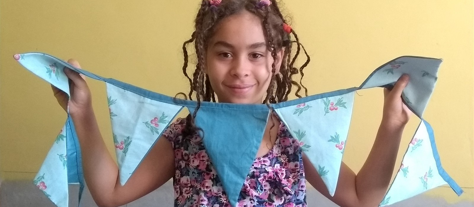 Young girl holding blue and floral patterned bunting