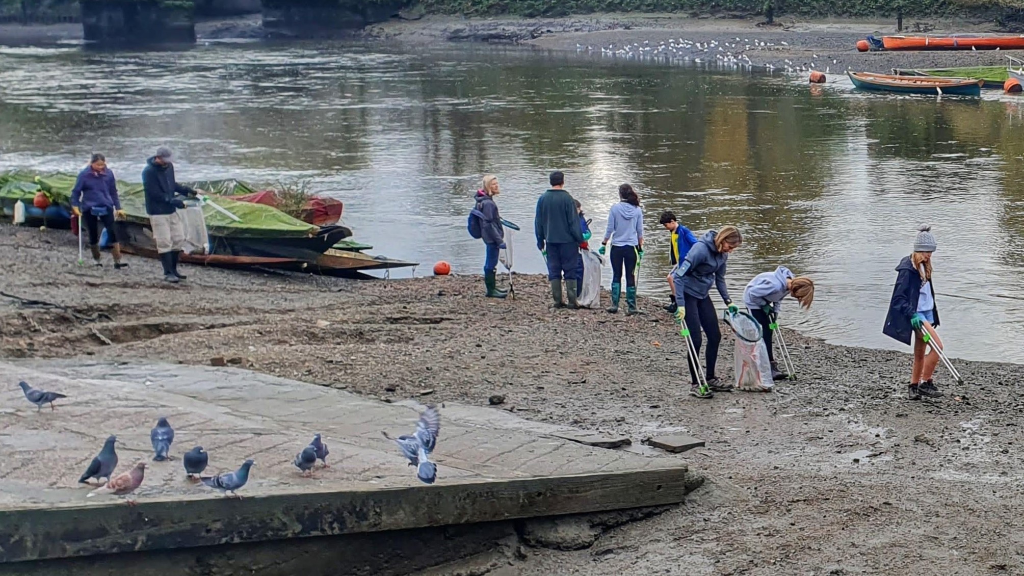 People with litter pickers on the foreshore of the River Thames near Richmond Bridge.